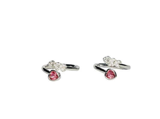Pair of silver toe rings with pink gemstones on a light gray background